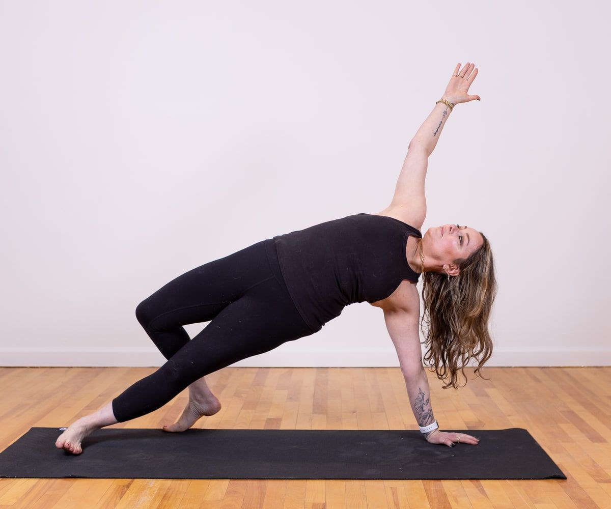 Deena Freed in a side-bending yoga pose on a mat.