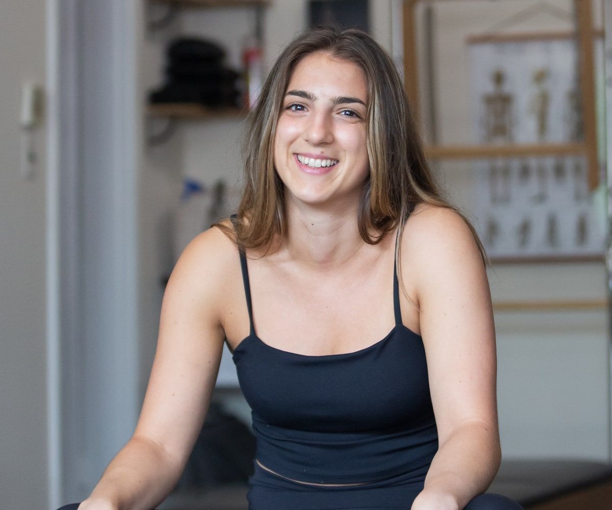 Emma Newell, smiling, seated in a bright studio.
