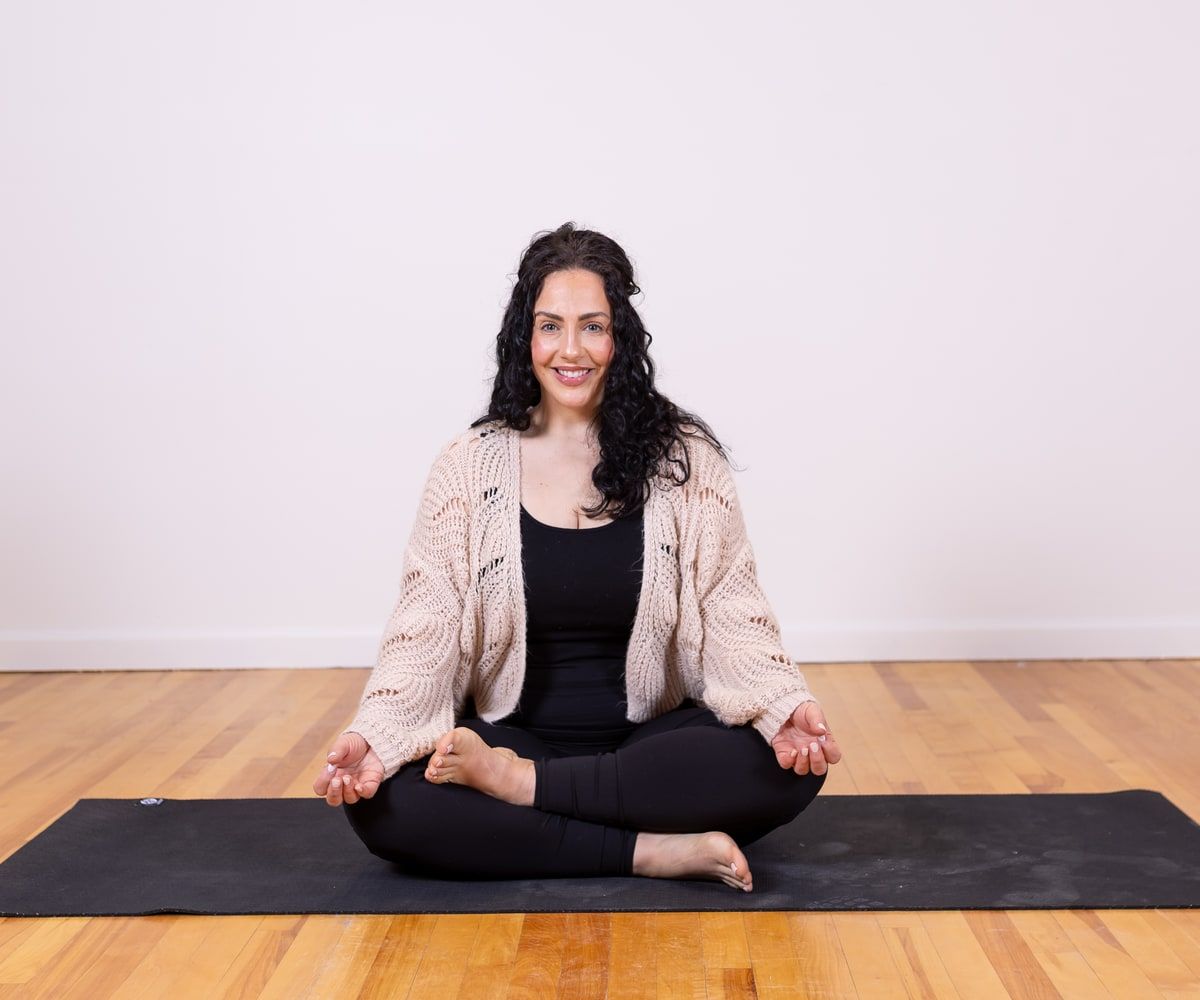 Francesca Defabritiis seated on a yoga mat, smiling.