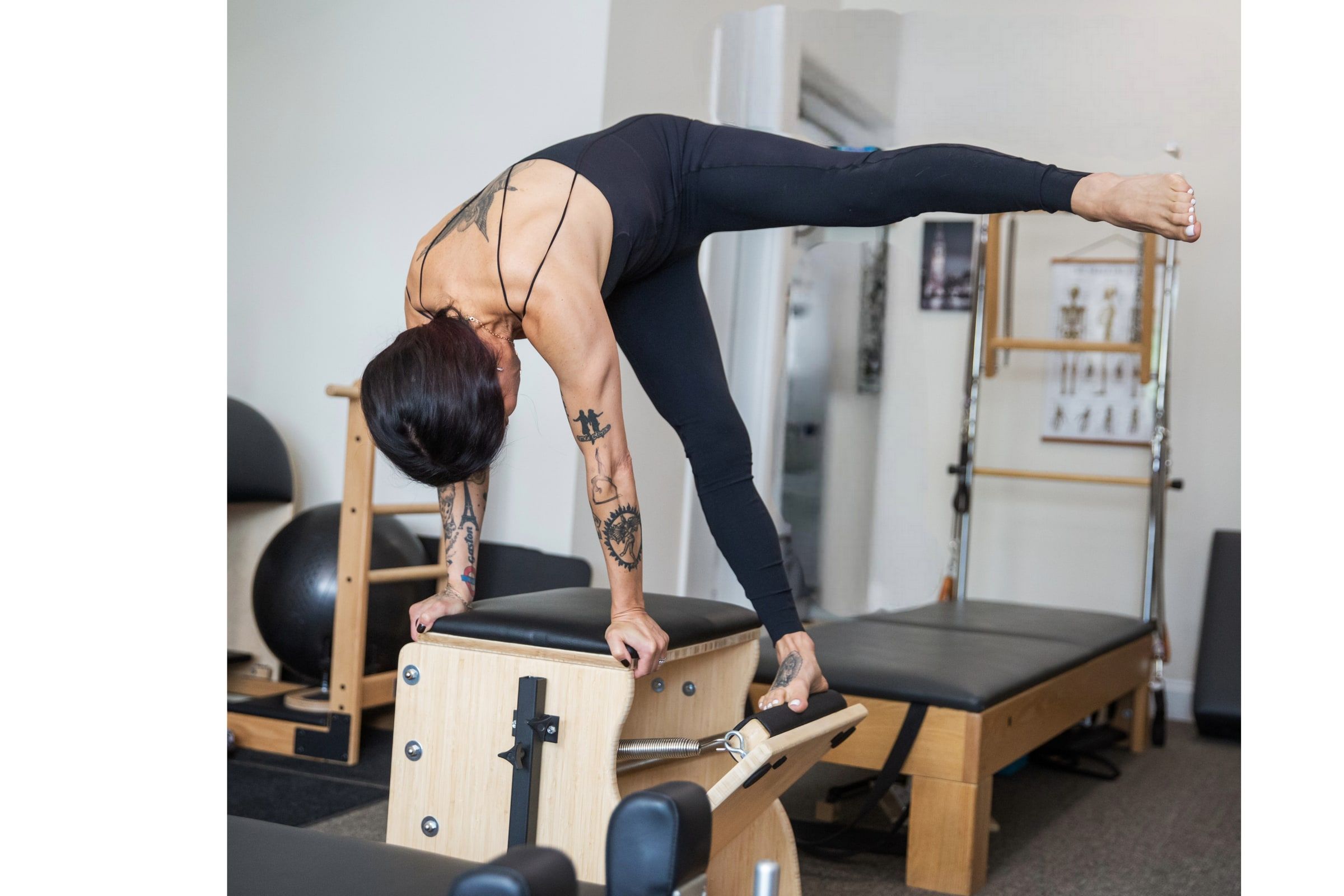 Karina Bergevin folded forward over a Pilates Wunda chair, hands on the pedal, in the OWL studio.