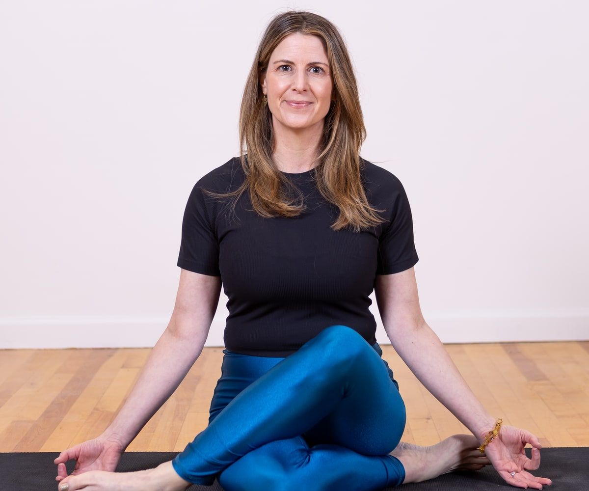 Joanna Scott seated on a yoga mat, smiling.