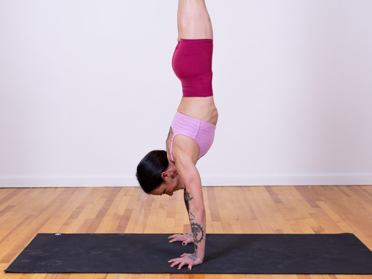 A student in a forearm stand against a dark backdrop.